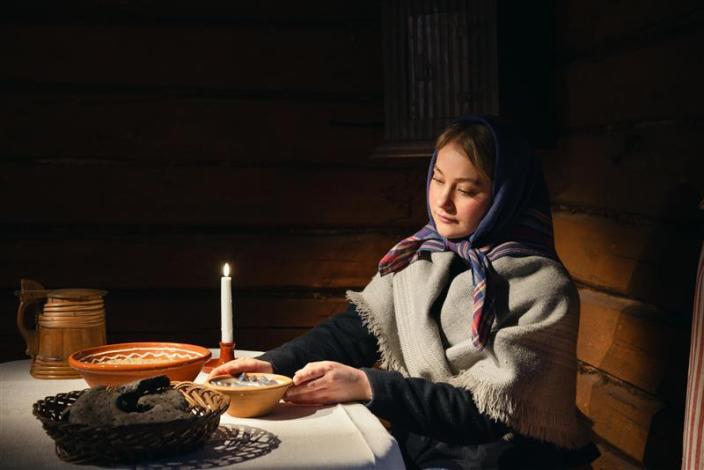 Luostarinmäen museokortteli, nainen istuu ruokapöydän ääressä kynttilänvalossa. (Kuva: Ville Mäkilä)