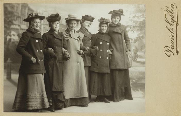 Mustavalkoisessa kuvassa kuusi pitkiin hameisiin ja takkeihin sekä hattuihin pukeutuneita naisia. (Kuva: Daniel Nyblin / Turun kaupunginmuseo, valokuvakokoelmat)