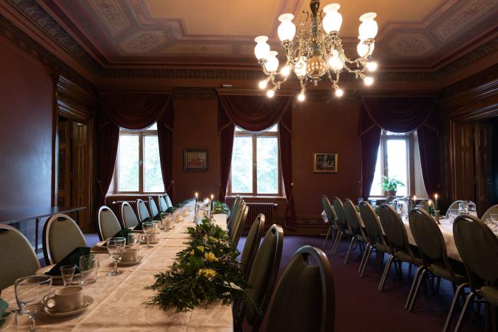 En stämningsfullt upplyst festlokal där borden är dukade för festmiddag. (Foto: Joonas Mäkivirta)
