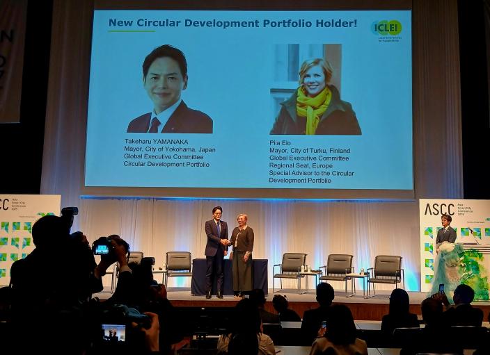 Mayors of Turku and Yokohama shake hands on a stage with and audience watching. (Picture: Risto Veivo)