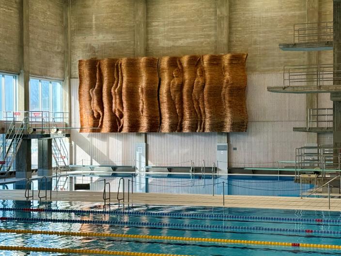 Puureliefi esittää altaaseen sukeltavia ja pinnalle kohti nousevia alastomia ihmishahmoja. (Kuva: Raakkel Närhi)