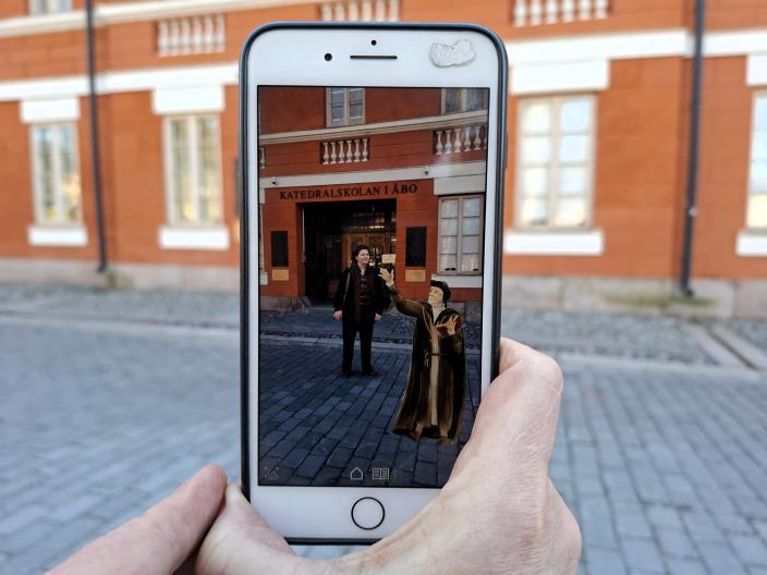 Katedralskolanin edustalta otettu kuva uudesta Mikael Agricolan åppi-hahmosta, vierellä hahmon tekijä Sebastian Helamaa. (Kuva: Teija Murmann)