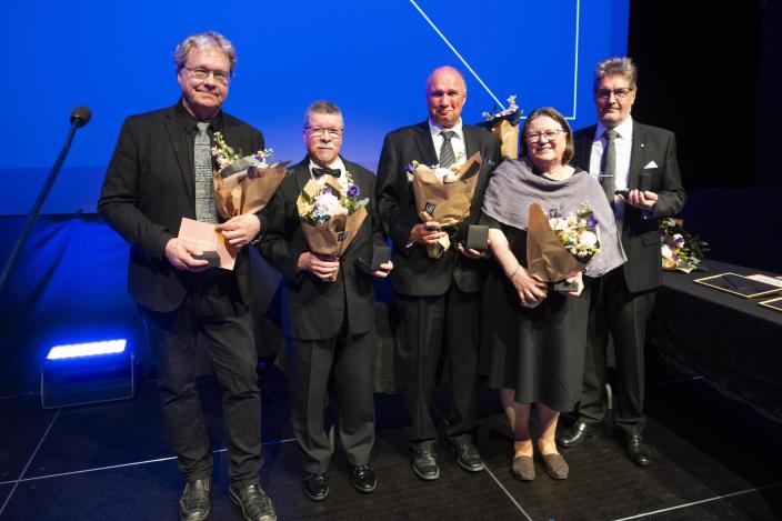 Viisi henkilöä lavalla, heillä on kukkakimput käsissään. (Kuva: Veera Korhonen, Suomen Museoliitto)