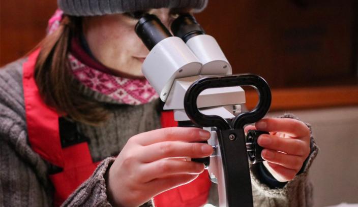 Opiskelija tutkii merestä löytyneitä näytteitä mikroskoopilla.  (Kuva: Aino Ruokonen)