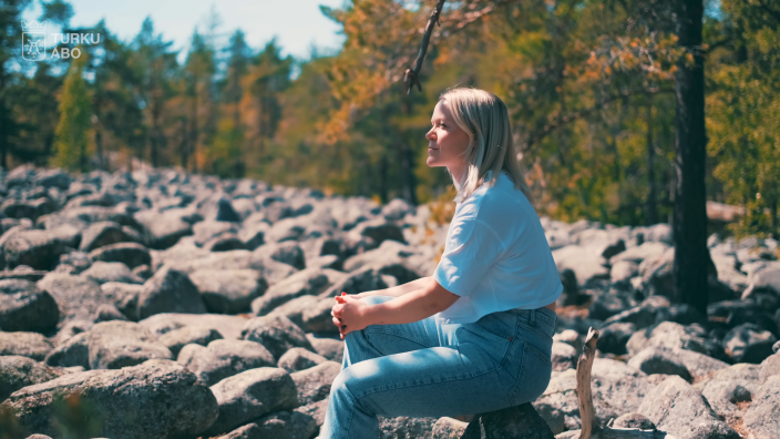 Nainen istuu Nunnavuoren pirunpellon laidalla.