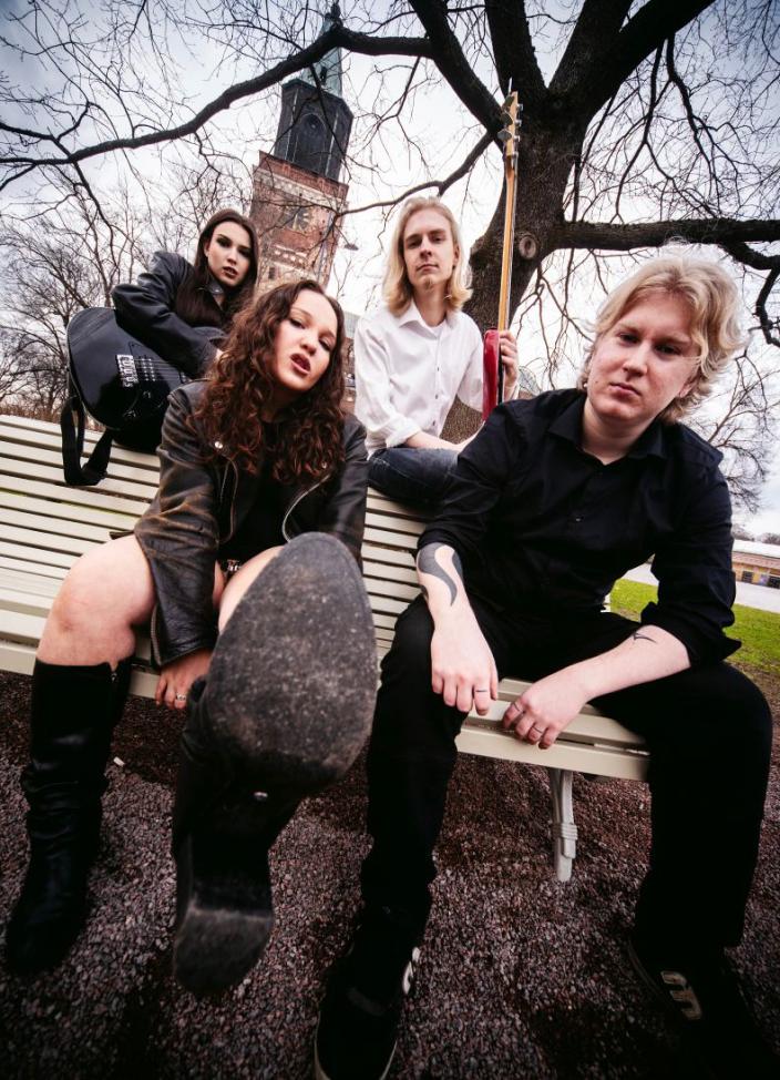 Kuvassa neljä nuorta istuu puistonpenkillä. Taustalla on Turun tuomiokirkko. (Kuva: Juha Kurri)