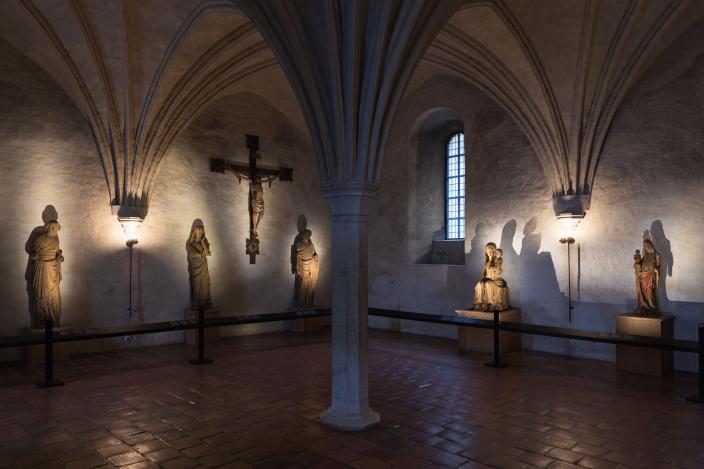 Yleisnäkymä tunnelmallisesti valaistusta Nunnakappelista, jossa keskiaikaisia puuveistoksia esillä. (Kuva: Ville Mäkilä)