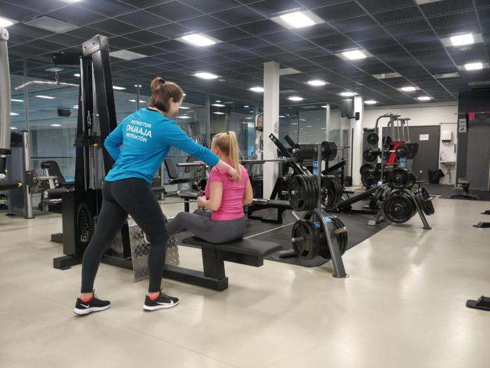 Ohjaaja opastaa aloittelijaa kuntosalilla. (Kuva: Susanna VUori)