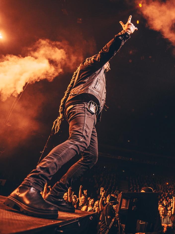 Kuvassa on rock-laulaja lavalla, josta nousee oranssia savua.