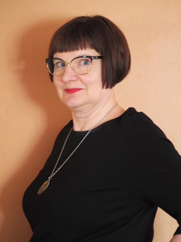 Silmälasipäinen, mustaan pukeutunut lyhythiuksinen henkilö jolla medaljonkiriipus. (Kuva: Turun kaupunginmuseo)