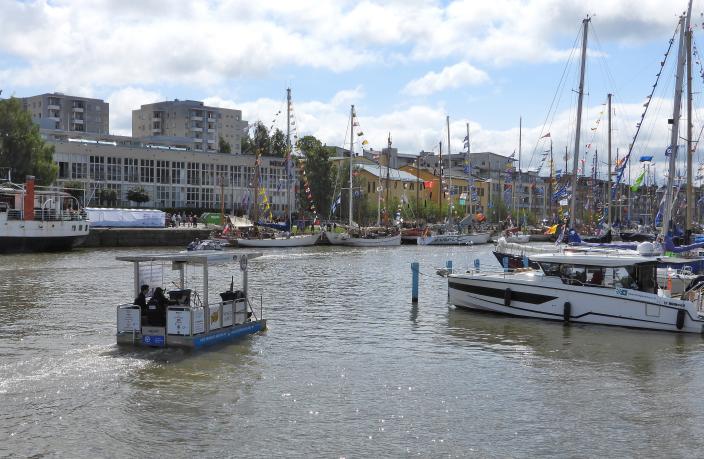 Roska-alus lipuu joessa. Taustalla veneitä ja kerrostaloja. (Kuva: Pidä Saaristo Siistinä ry)