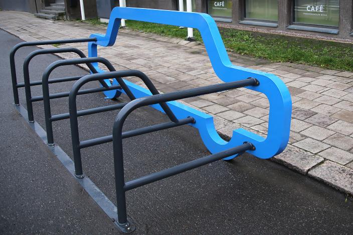 Sinisen auton mallinen sähköpotkulautateline Henrikinkadun varrella. (Foto: vilhelmina vesanen)