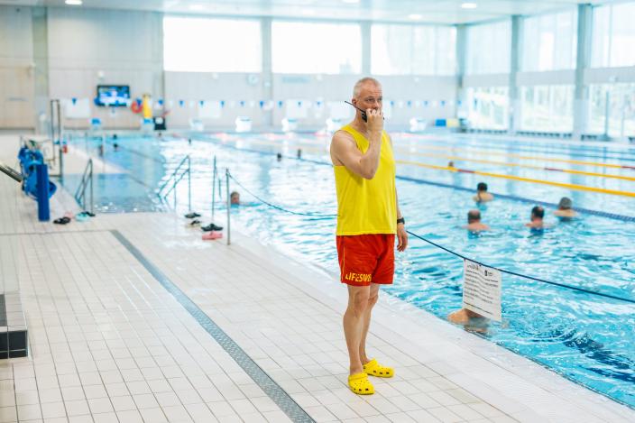 Uimavalvoja seisoo uima-altaan vieressä ja pitää kädessään radiopuhelinta (Kuva: Heikki Räisänen)