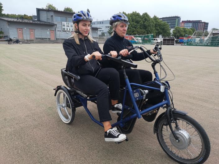 Two women sit on a side-by-side bike and pedal. (Picture: Johanna Friman)