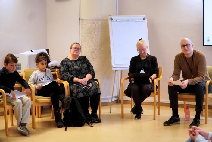 Lapsia ja aikuisia istuu ringissä tuoleilla. (Kuva: Maiju Teuho)