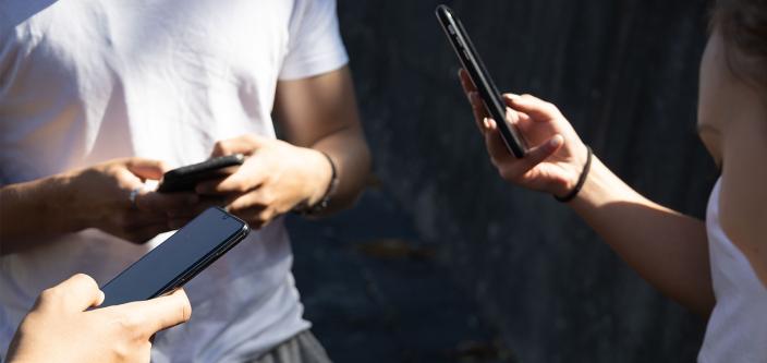 Kolme ihmistä näppäilee älypuhelimia.