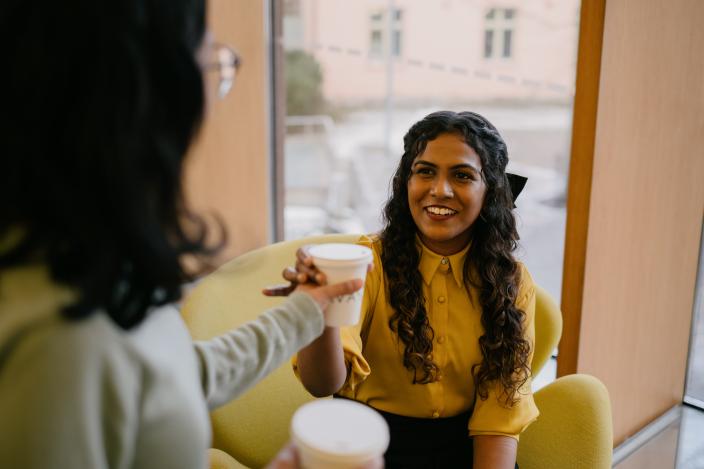 Kaksi tummahiuksista henkilöä istuu Turun pääkirjastossa. (Kuva: Antti Merisaari / Mama Creative)