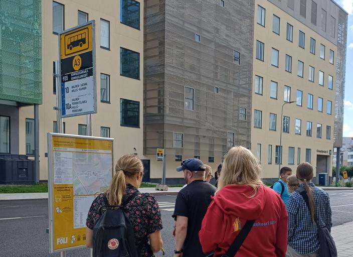 Ihmisiä Turun kaupungin bussipysäkillä katsomassa karttaa.  
