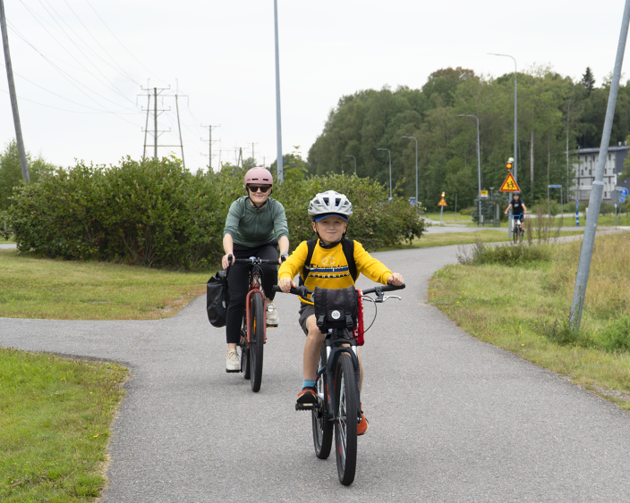 Äiti ja lapsi pyöräilevät pyörätiellä kesäisellä säällä. (Kuva: Iiris Yli-Junnila)