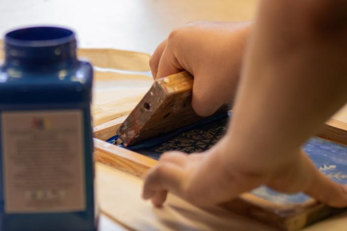 Kuvassa henkilö painaa lumihiutaleen kuvaa kangaskassiin. (Foto: Aleksandra Ketonen)