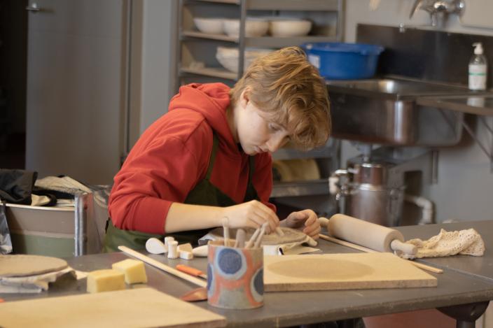 Nuori tekee savityötä levytekniikalla Vimman savipajassa pöydän ääressä. (Foto: Aleksandra Ketonen / Fendari)