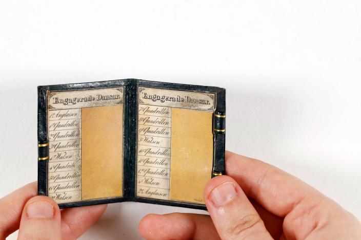 Tulitikkurasian kokoinen tanssikortti avattuna, aukeamalla eri tanssien nimiä. (Kuva: Anna Saarikko, Turun kaupunginmuseo)