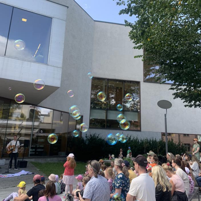 Ihmisiä pääkirjaston pihalla kesällä kirjaston tapahtumassa. (Kuva: Mette Seppälä)