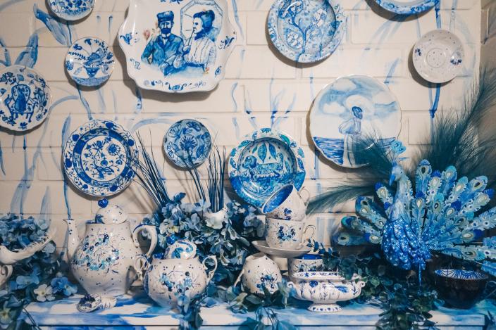 Sini-valkoisella koristeltuja astioita ja esineitä Aikamatka 20360 -tilataideteoksen huoneessa.
