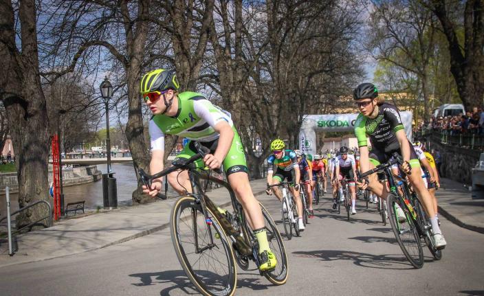 Kypäräpäiset pyöräilijät kovassa vauhdissa Aurajoen rannalla.