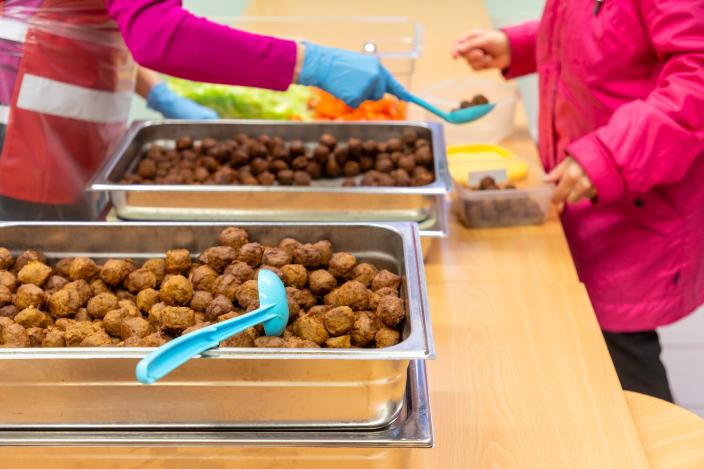 The food aid distributor serves meatballs to the customer's plate. (Picture: Timo Jakonen)