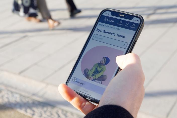 Käsi pitelee puhelinta, jonka ruudulla näkyy Turun verkkosivusto (Kuva: Kaisa Koski)
