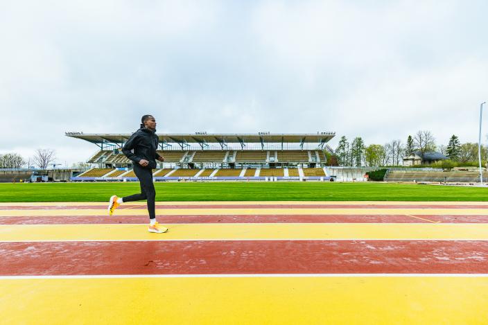 En person springer på stadionens färgglada löparbana. I bakgrunden syns en läktare och träd. (Foto: Heikki Räisänen)