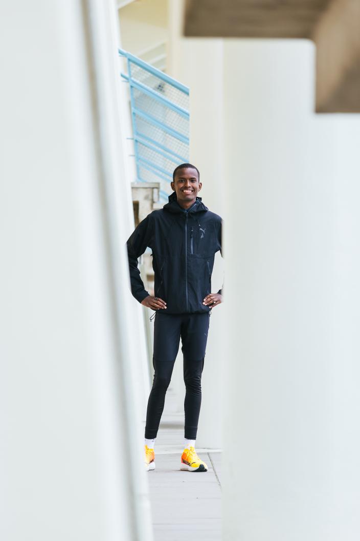 Henkilö seisoo valkoisten seinien edessä kädet lanteillaan ja katsoo kameraan hymyillen. (Kuva: Heikki Räisänen)