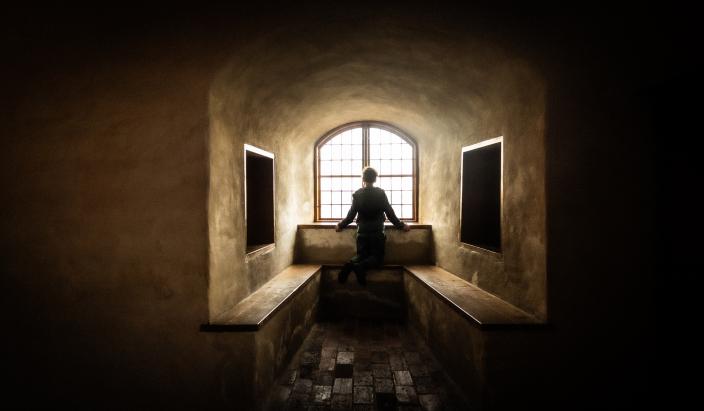 Henkilö seisoo Turun linnan ikkunasyvennyksessä ja katselee ulos.  (Kuva: Bengt Selin)