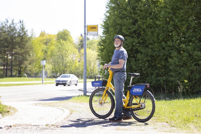 Kuvassa mies on keltaisen kaupunkipyörä föllärin päällä ja katsoo eteenpäin tien vierellä. (Kuva: Suvi Elo)