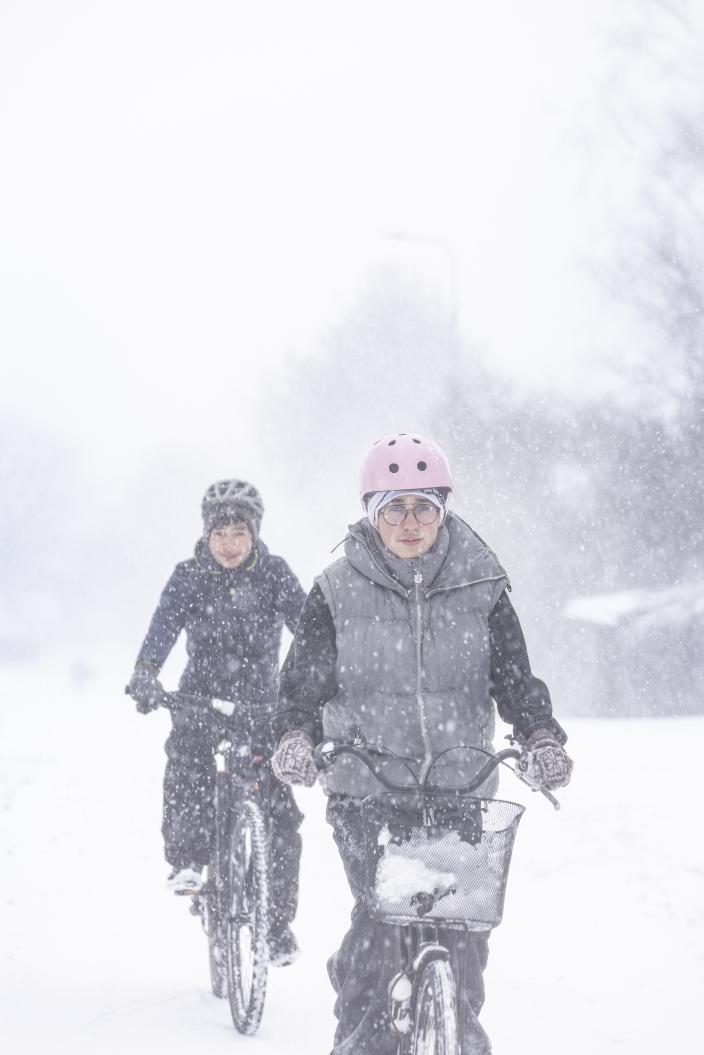 Kaksi pyöräilijää pyöräilemässä lumisateessa. (Kuva: Suvi Elo)