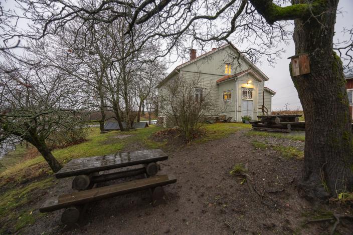 Puutalo puiden siimeksessä. Pihalla istuskeluryhmiä. (Kuva: Mika Okko)