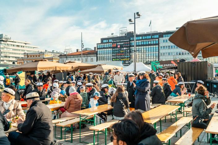 Kuva vapputorilta, ihmisiä ihtumassa pöytien ääressä ylioppilaslakit päässä.