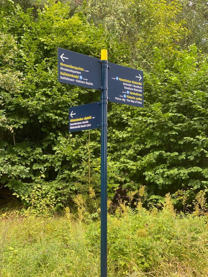 Tre vägvisarskyltar med text. I bakgrunden finns träd och vegetation. (Foto: Focus-Video)