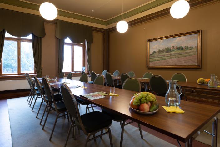 Kaksi kokouspöytää vanhan kivitalon salissa. (Foto: Joonas Mäkivirta)