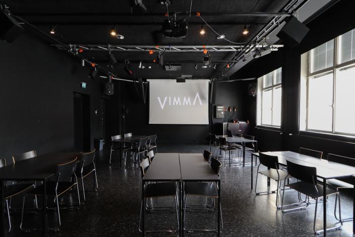 Vimman teatteritilassa pöytäryhmiä ja valkokangas. (Kuva: Oona Kokko)