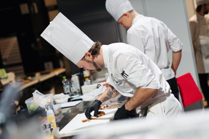 Kaksi kokkia valmistamassa annoksia keittiössä.