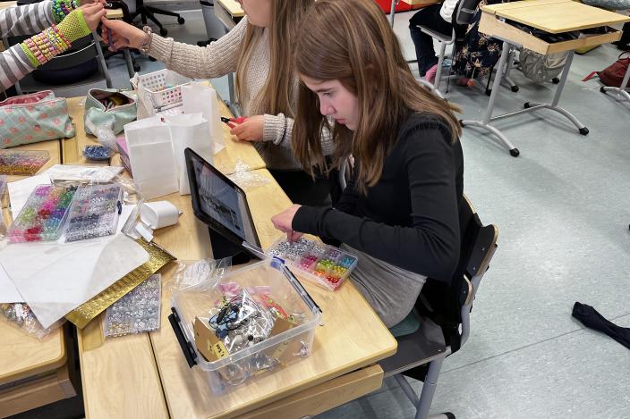 Alakoulun oppilas suunnittelee korumallia ja katsoo ohjetta tabletilta. (Kuva: Hannele Sivonen)